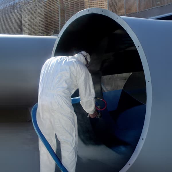 Infraestructura hídrica Aplicador técnico proyectando poliurea en el interior de una tubería de gran diámetro para protección anticorrosiva y mejoramiento de flujo.
