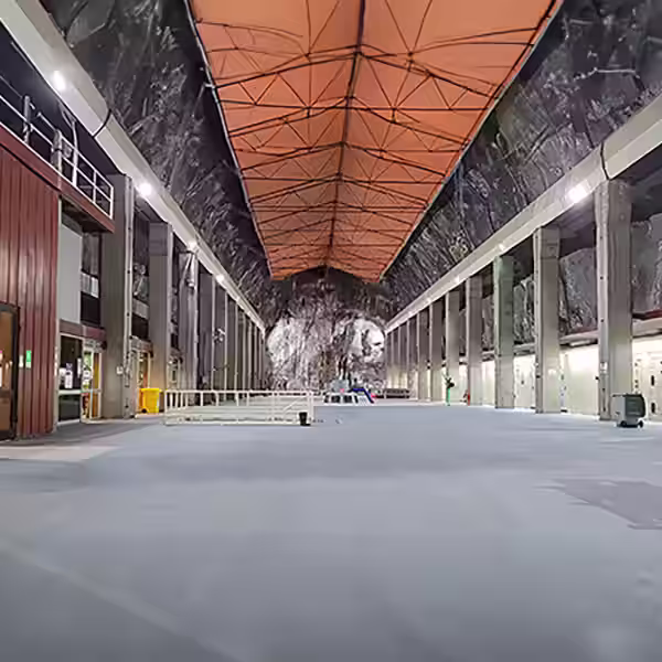 Industrias Revestimiento técnico continuo sobre un piso industrial de hormigón con demarcación de seguridad amarilla para pasillo de tránsito intensivo.